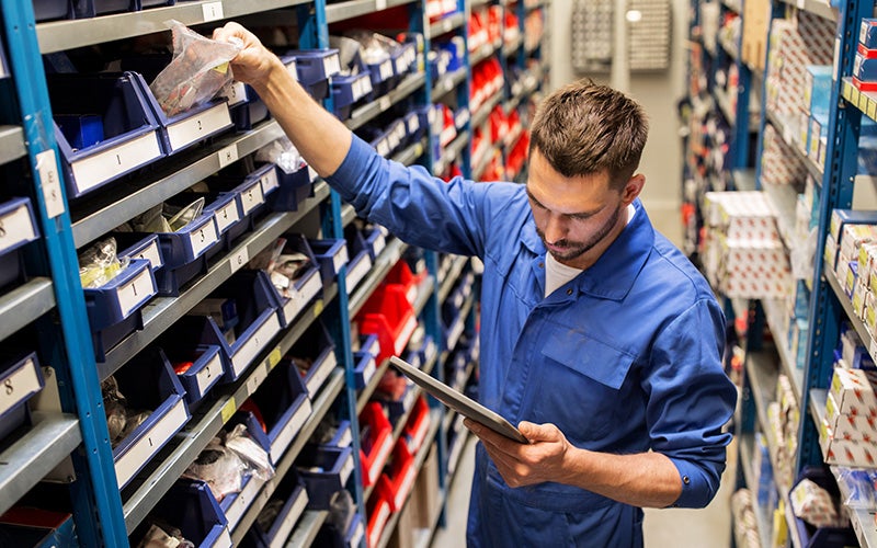 Technician reviewing parts inventory on a tablet in an auto service center